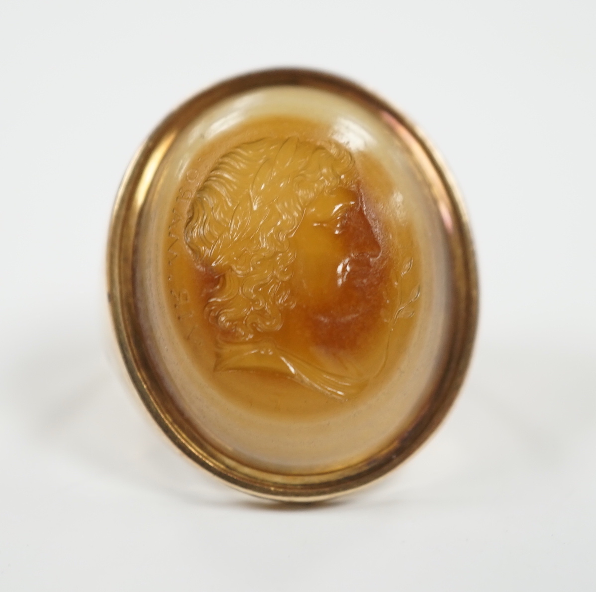 An early 20th century yellow metal and banded agate intaglio ring, carved with the head of a gentleman to sinister, size L, gross weight 8.1 grams.